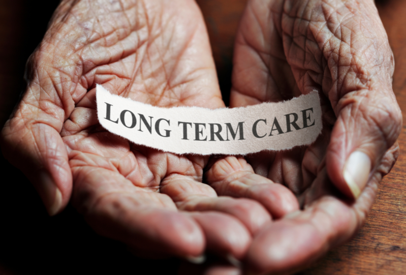 Long Term Care written on a strip of paper held in open hands