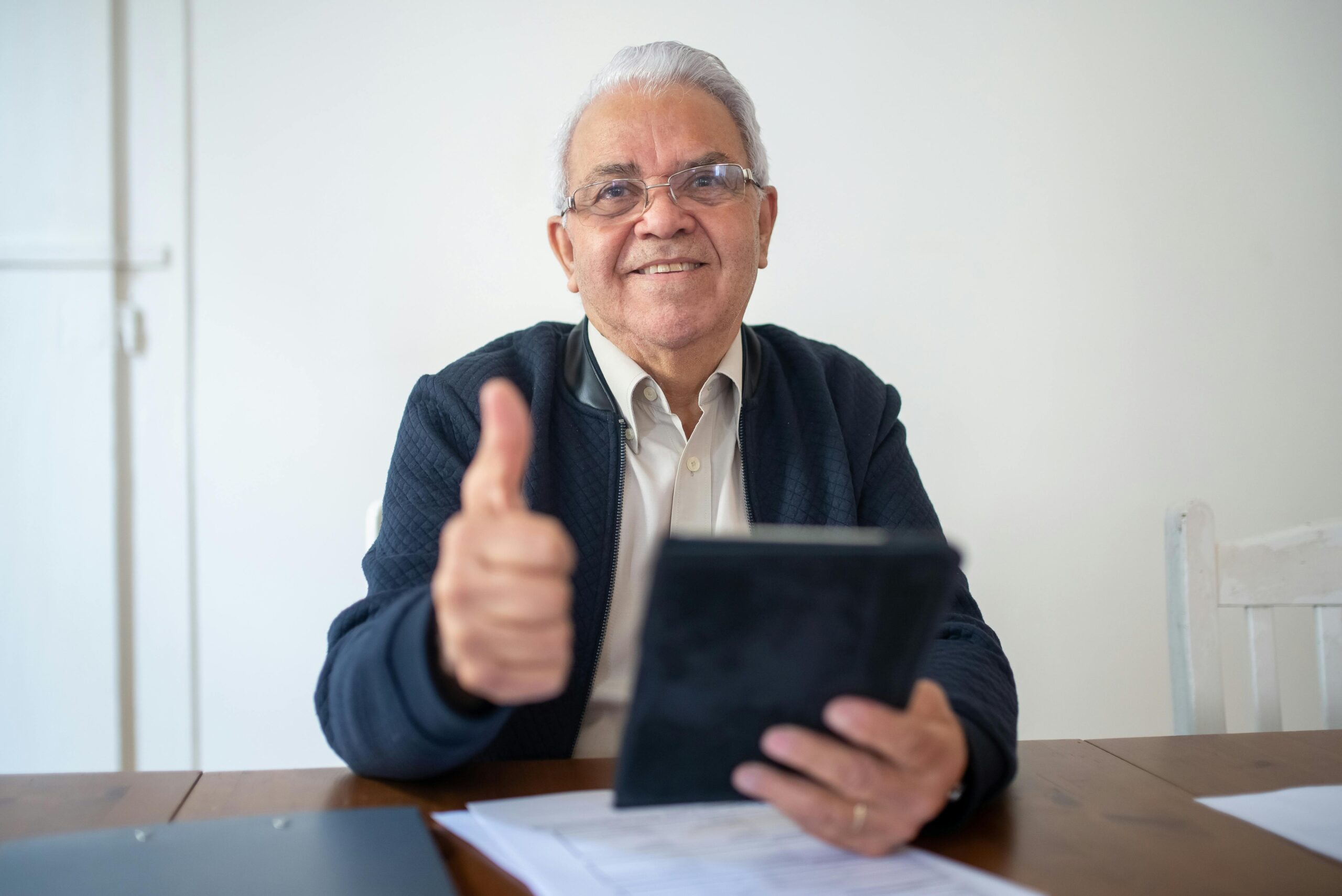 Elderly gentleman reviewing Medicare documents with a smile and thumbs up