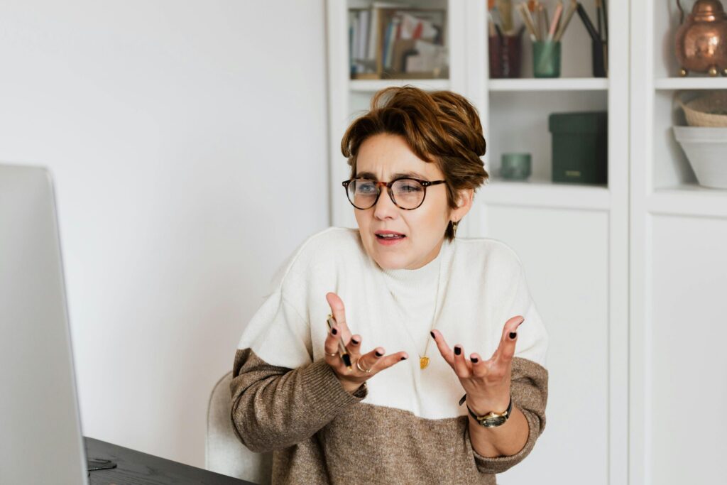 Woman shrugging while looking at computer