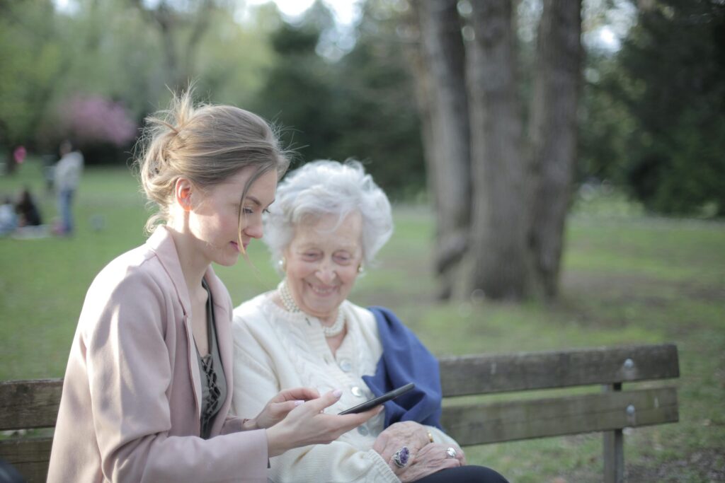 Young woman helping read mobile device for senior