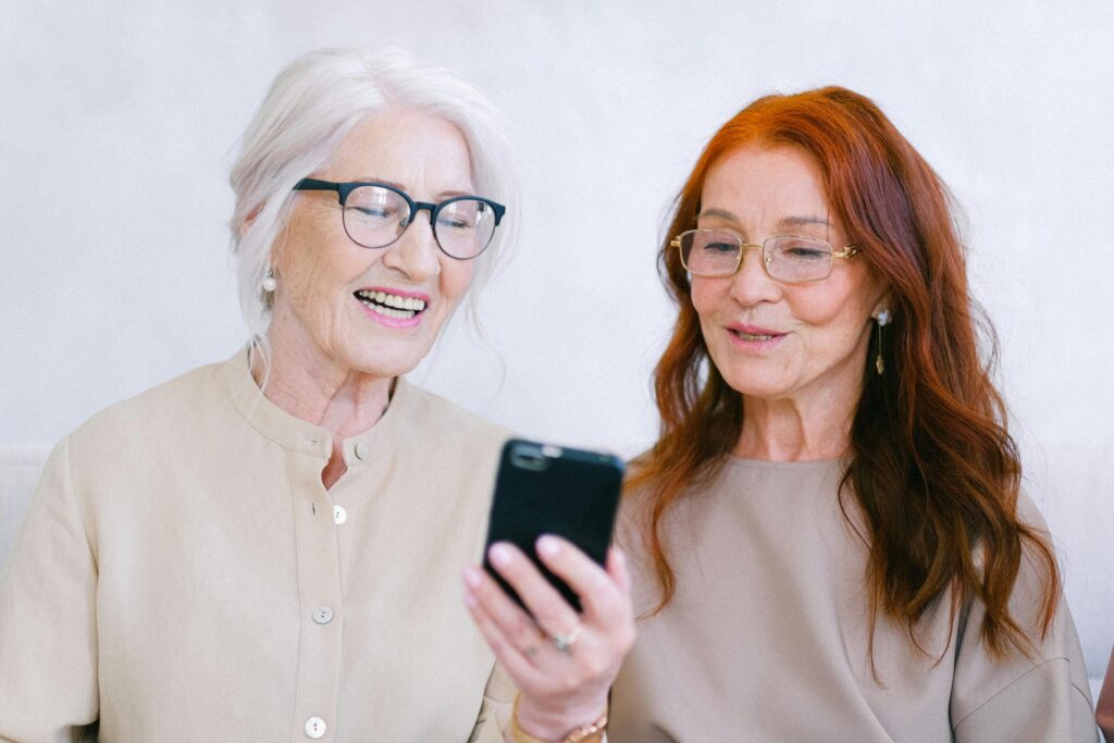 Two elderly woman looking at phone and smiling