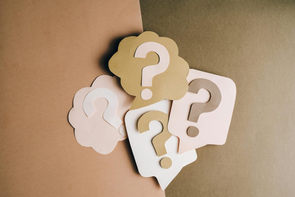 Medicare Help - Question mark cutouts in layered paper craft style on a brown backdrop, conceptual art.