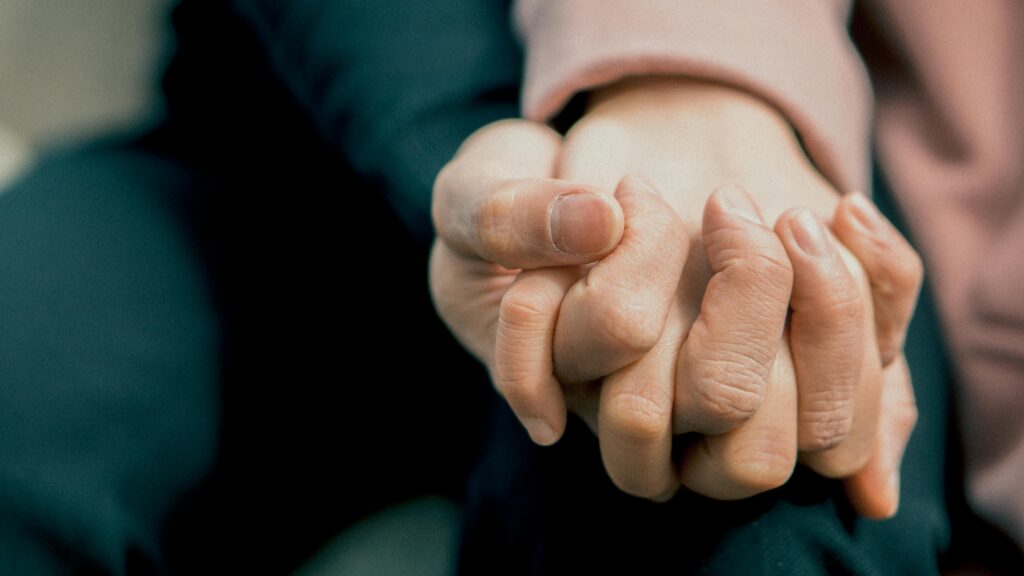 A close-up photo capturing two adult hands holding each other, symbolizing love and support.